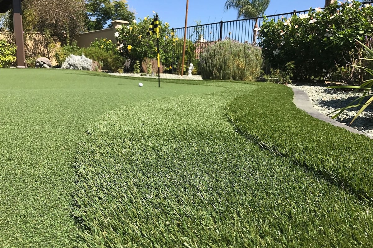 Custom putting green wrapping around a backyard patio by Panjia Outdoors